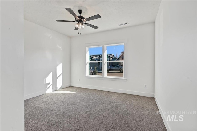 carpeted spare room featuring a textured ceiling, a ceiling fan, visible vents, and baseboards