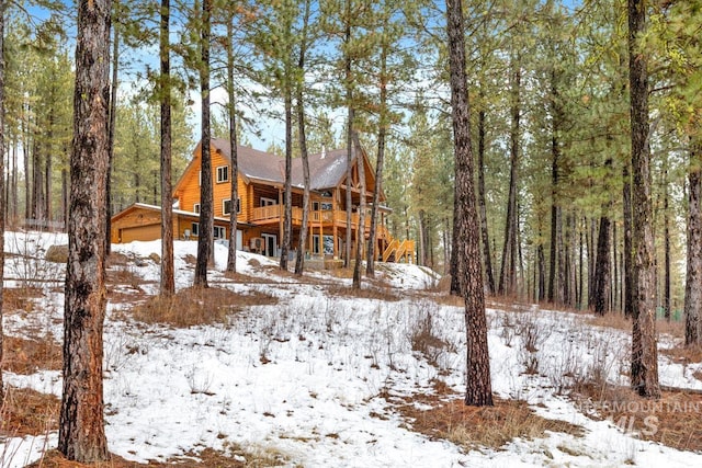 snow covered back of property featuring a wooden deck