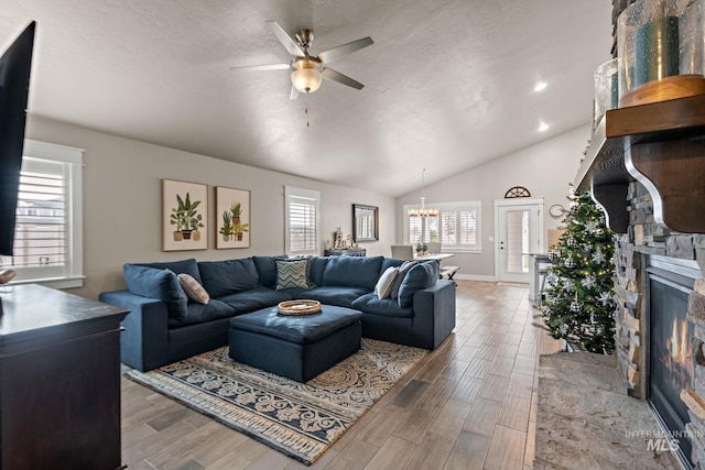 living room with a fireplace, hardwood / wood-style floors, ceiling fan with notable chandelier, and vaulted ceiling