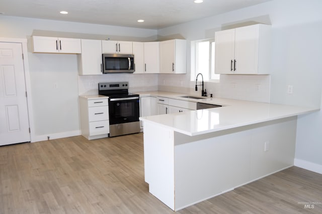 602 E Freeport St, Caldwell, ID 83605 - kitchen with appliances with stainless steel finishes, a sink, a peninsula, tasteful backsplash, and light wood-style flooring