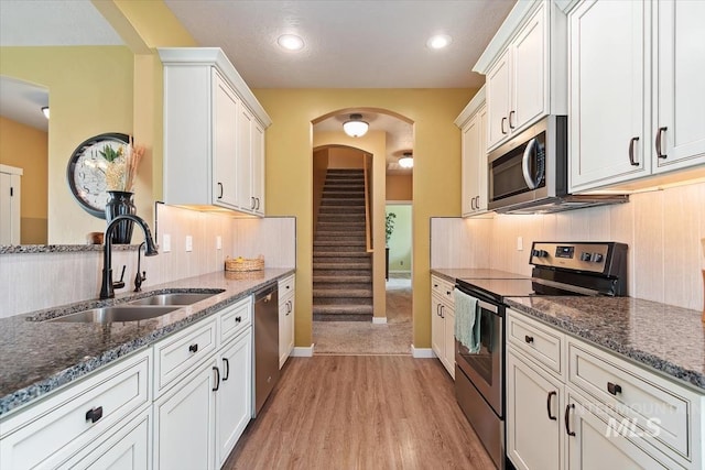 27482 Warren Ln, Wilder, ID 83676 - kitchen featuring appliances with stainless steel finishes, light wood-style floors, dark stone countertops, white cabinetry, and recessed lighting