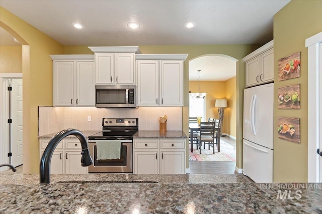 27482 Warren Ln, Wilder, ID 83676 - kitchen with stainless steel appliances, arched walkways, recessed lighting, stone counters, and white cabinetry
