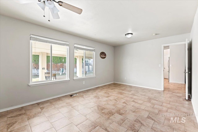 empty room with visible vents, baseboards, and ceiling fan