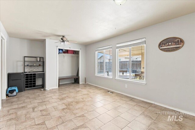 unfurnished living room with visible vents, baseboards, and ceiling fan