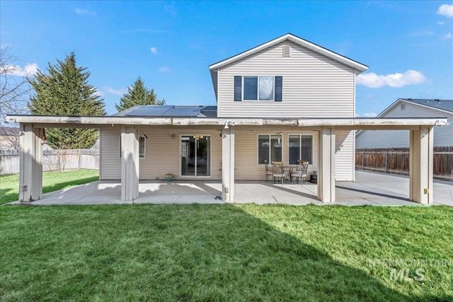 back of house featuring a yard, fence, solar panels, and a patio area