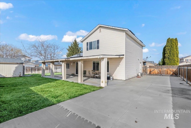 rear view of house with a lawn, a fenced backyard, a patio area, an outbuilding, and a gate