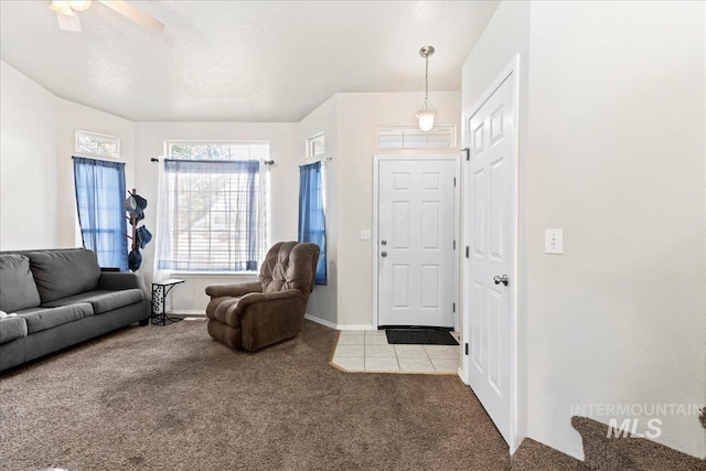 living room with ceiling fan, carpet flooring, baseboards, and a textured ceiling