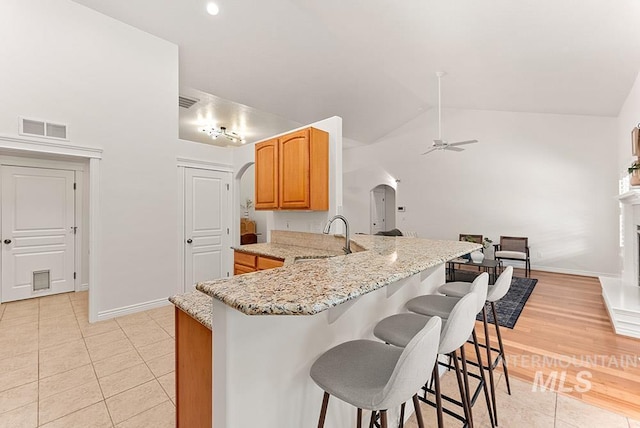 1730 W Glade Creek St, Meridian, ID 83646 - kitchen with arched walkways, light tile patterned floors, a ceiling fan, a peninsula, and a kitchen bar