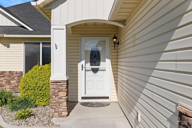 property entrance featuring board and batten siding and roof with shingles