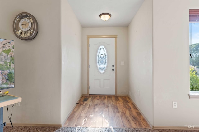 doorway with plenty of natural light, wood finished floors, and baseboards