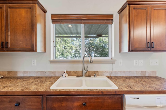 kitchen with a sink, dishwasher, healthy amount of natural light, and brown cabinets