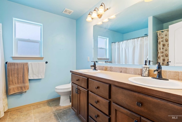 bathroom with baseboards, toilet, and double vanity