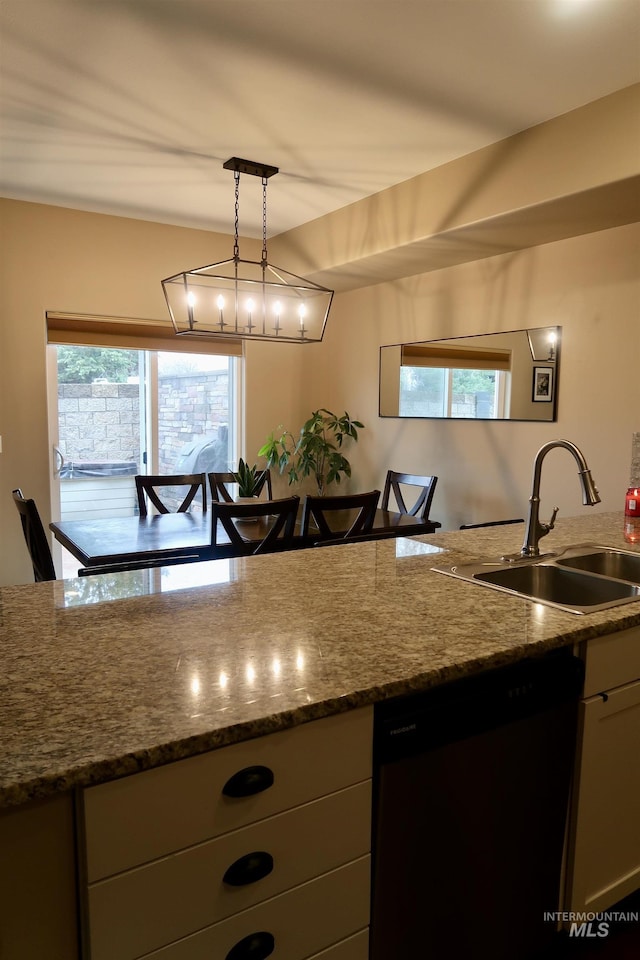 kitchen featuring sink, dark stone countertops, hanging light fixtures, black dishwasher, and plenty of natural light