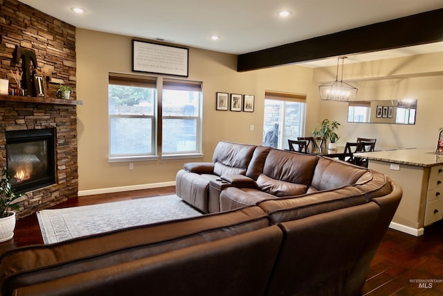 living room with a fireplace, beamed ceiling, and dark wood-type flooring