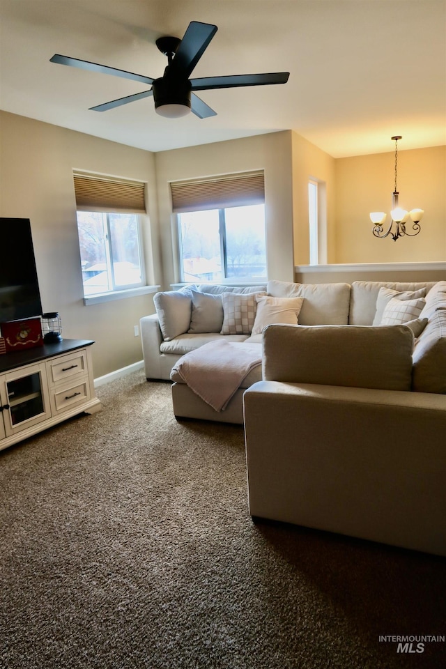 carpeted living room featuring ceiling fan with notable chandelier