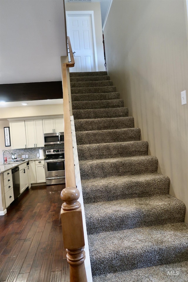 stairway featuring hardwood / wood-style flooring and sink