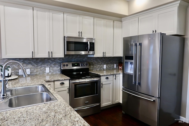 kitchen featuring white cabinets, sink, tasteful backsplash, light stone counters, and stainless steel appliances