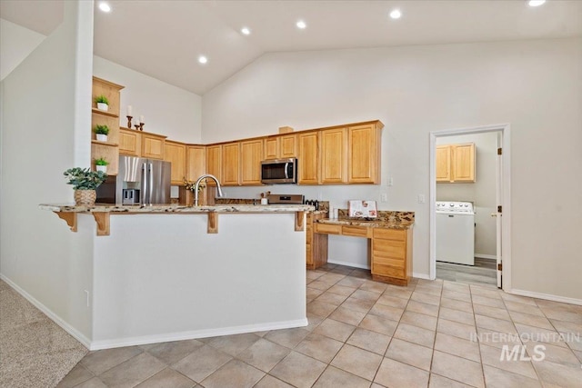 kitchen featuring washer / dryer, a kitchen breakfast bar, a peninsula, stainless steel appliances, and open shelves