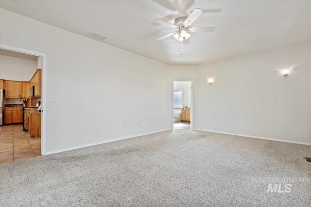 unfurnished room featuring light carpet, visible vents, baseboards, ceiling fan, and a textured ceiling