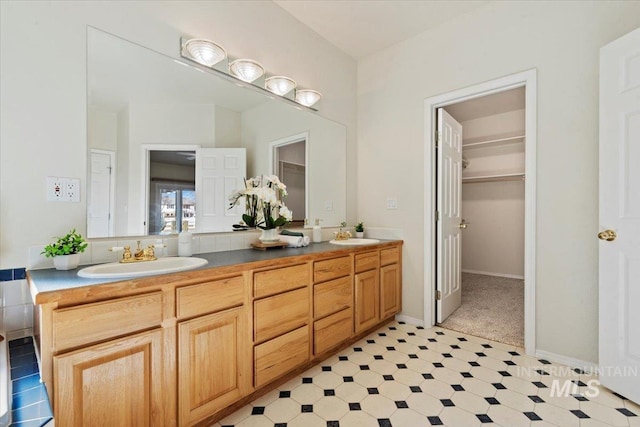 bathroom with baseboards, double vanity, a sink, and tile patterned floors