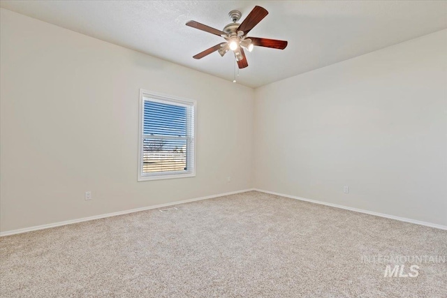 carpeted empty room featuring baseboards and a ceiling fan