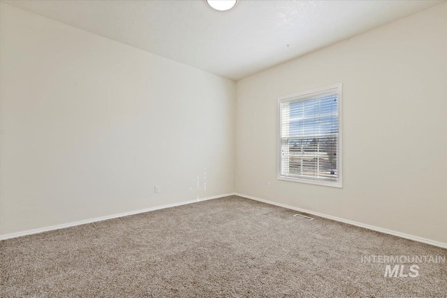 unfurnished room with carpet, visible vents, and baseboards