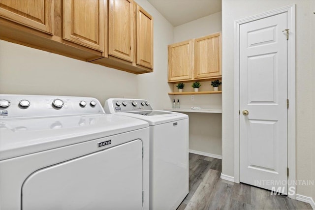 laundry room featuring light wood-style flooring, cabinet space, washer and clothes dryer, and baseboards