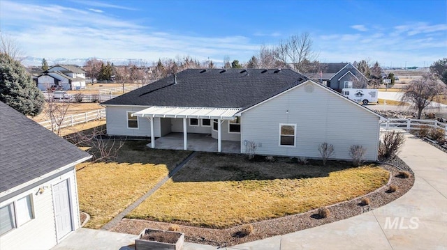 back of house featuring a patio area, roof with shingles, fence, and a yard