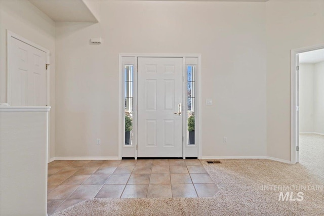 entryway with tile patterned flooring, carpet flooring, visible vents, and baseboards