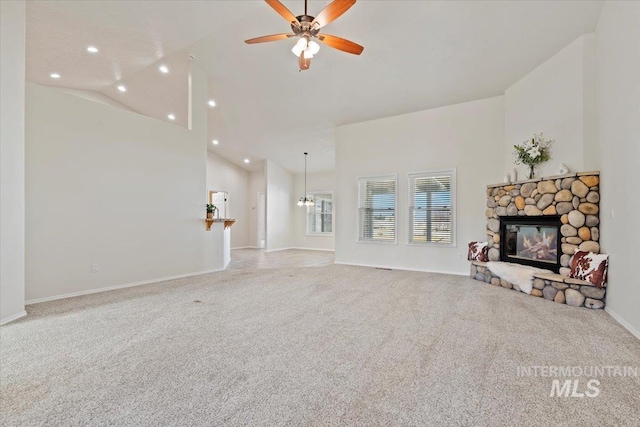 carpeted living room with ceiling fan with notable chandelier, high vaulted ceiling, a stone fireplace, and recessed lighting