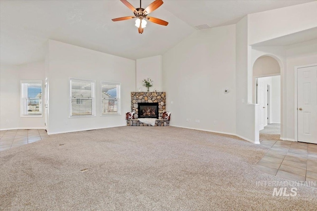 living room featuring light tile patterned floors, high vaulted ceiling, a stone fireplace, and light colored carpet