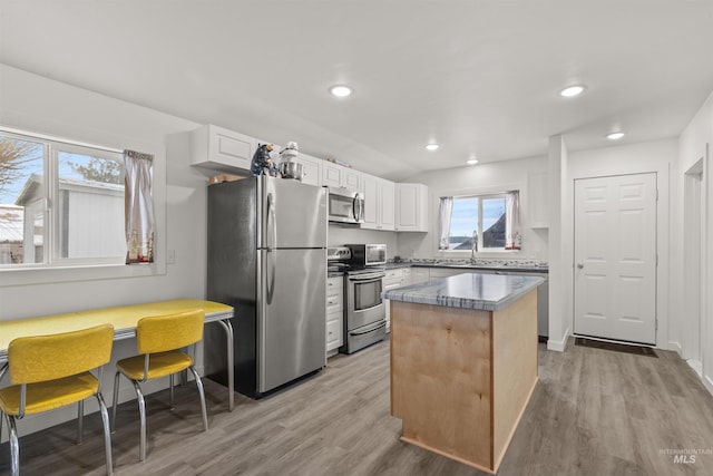 kitchen featuring white cabinets, appliances with stainless steel finishes, light wood-type flooring, and a center island