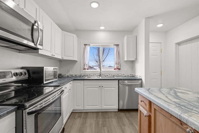 kitchen featuring white cabinetry, sink, stainless steel appliances, and light hardwood / wood-style flooring