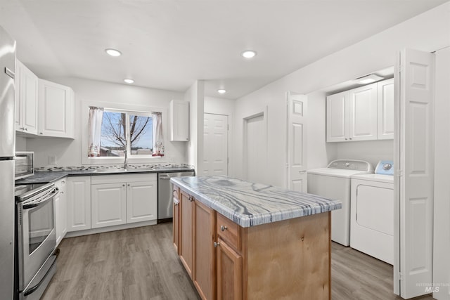 kitchen featuring stainless steel appliances, light hardwood / wood-style flooring, white cabinets, independent washer and dryer, and a kitchen island