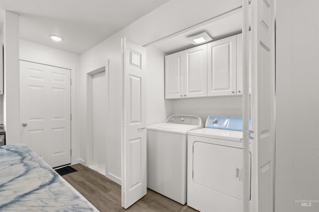 laundry area with washer and clothes dryer, cabinets, and light wood-type flooring