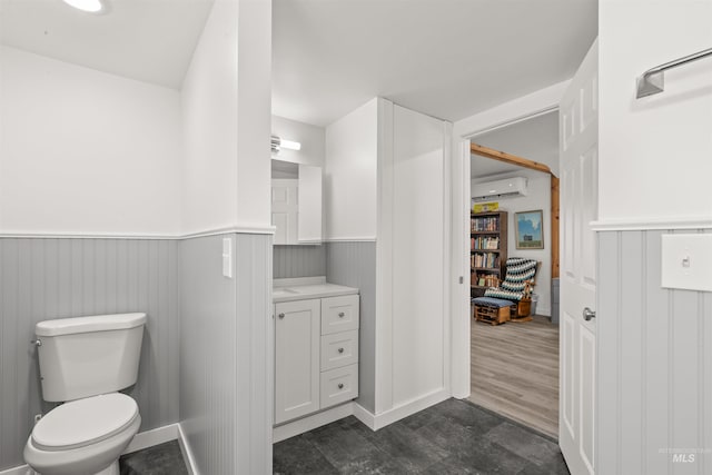 bathroom with a wall mounted AC, toilet, vanity, and hardwood / wood-style flooring