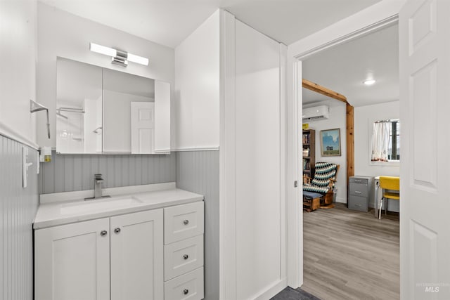 bathroom with an AC wall unit, vanity, and hardwood / wood-style flooring