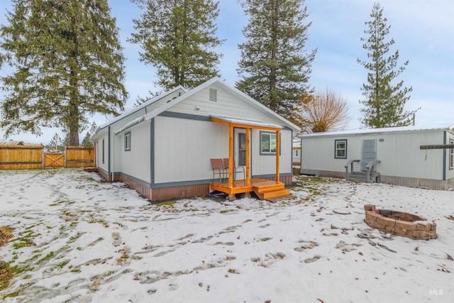 snow covered rear of property with a fire pit