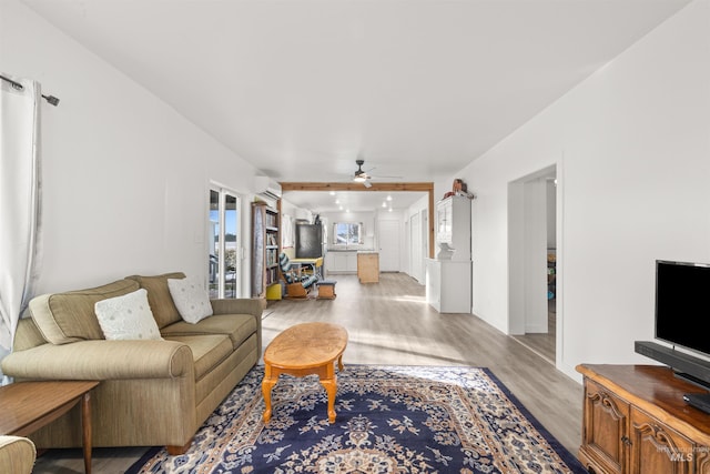 living room featuring an AC wall unit, ceiling fan, and light hardwood / wood-style flooring