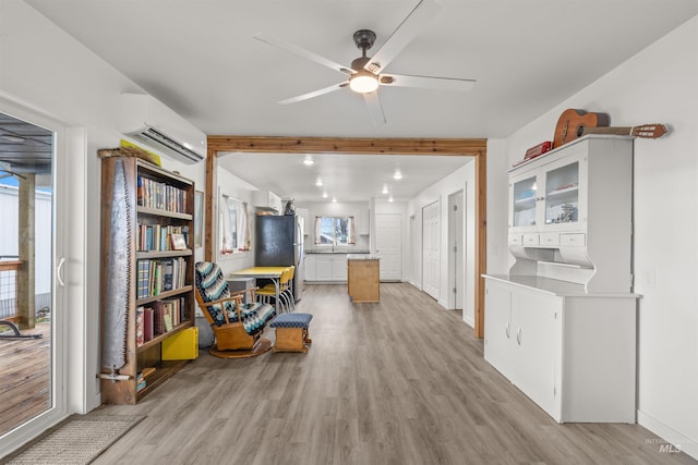 interior space with light hardwood / wood-style floors, a wall unit AC, and ceiling fan