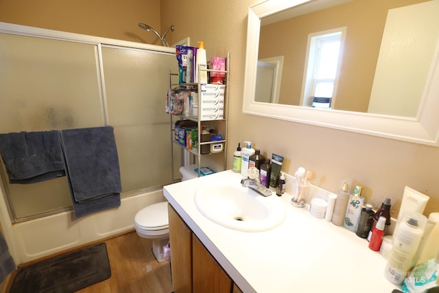 full bathroom featuring wood finished floors, combined bath / shower with glass door, toilet, and vanity