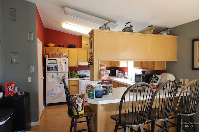 kitchen with a peninsula, light wood-style floors, white appliances, light countertops, and under cabinet range hood