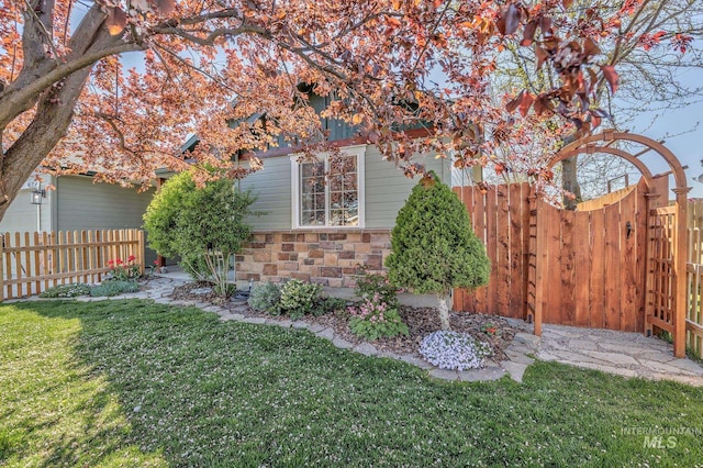 exterior space with a lawn, stone siding, and fence