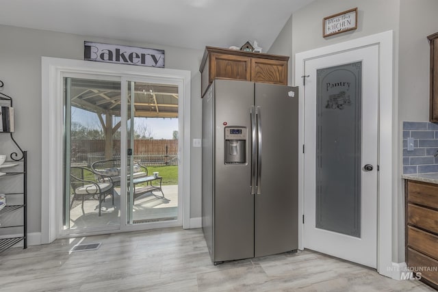 kitchen featuring light wood-type flooring, baseboards, visible vents, and stainless steel fridge