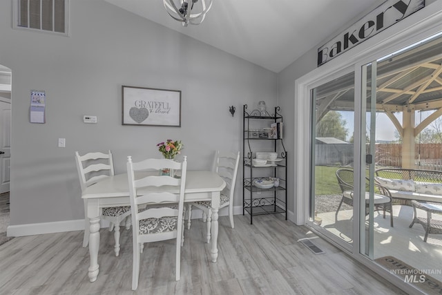 dining area featuring vaulted ceiling, wood finished floors, visible vents, and baseboards