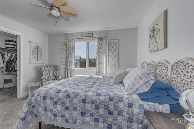 carpeted bedroom featuring a ceiling fan, baseboards, a closet, and a walk in closet