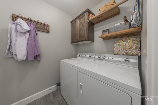 washroom featuring baseboards, washer and dryer, dark wood-type flooring, and cabinet space