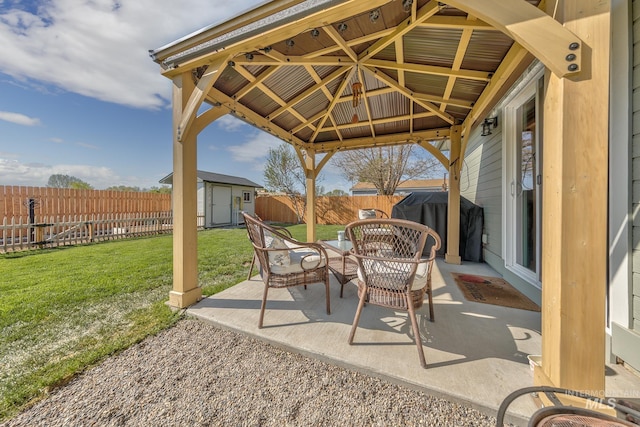 view of patio featuring a storage shed, an outbuilding, a fenced backyard, and a gazebo