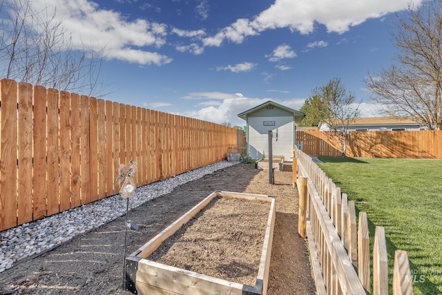 view of yard with a fenced backyard, a vegetable garden, a storage unit, and an outdoor structure
