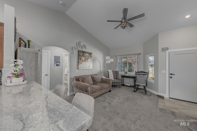 carpeted living area with arched walkways, baseboards, recessed lighting, ceiling fan, and high vaulted ceiling